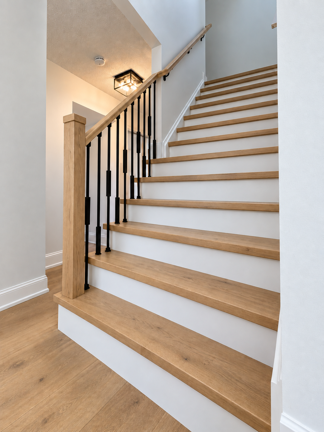 Completed Campbell staircase with natural oak treads, white risers, oak rails, and slim black balusters